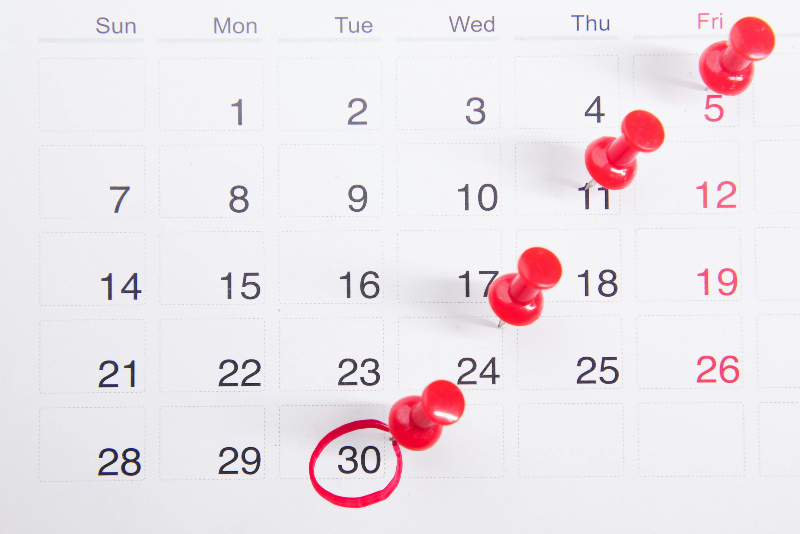 Services Close-up of a calendar with red push pins marking important dates, emphasizing deadlines.